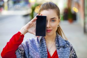 Young woman covers her face screen smartphone